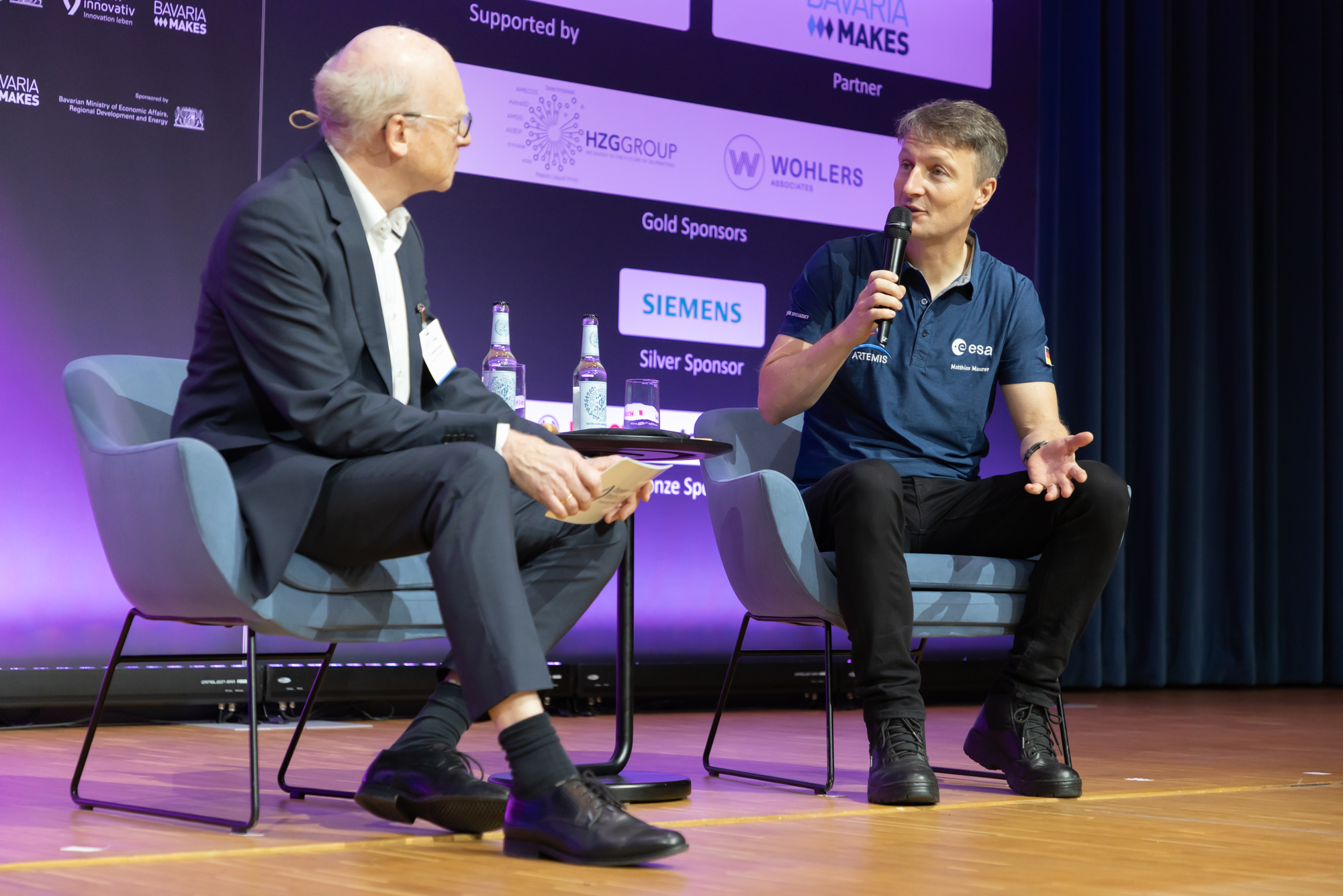 Zwei Personen sitzen auf der Bühne und führen ein Gespräch vor Publikum. Entstanden beim AM Kongress.