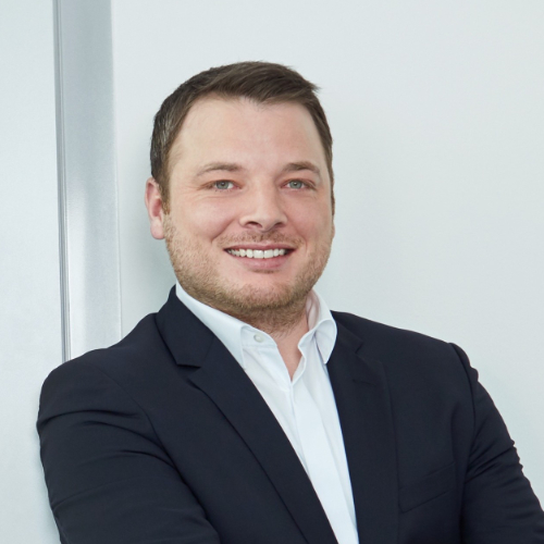 Das Bild zeigt einen lächelnden Mann im Anzug