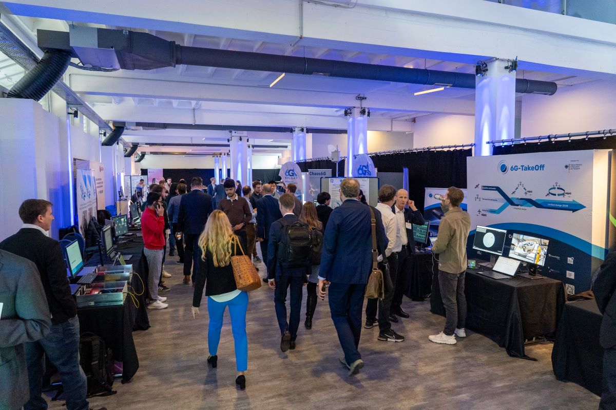 A look into one side of the Thinknet 6G Summit exhibition, showing the booths on the sides and people in the middle.