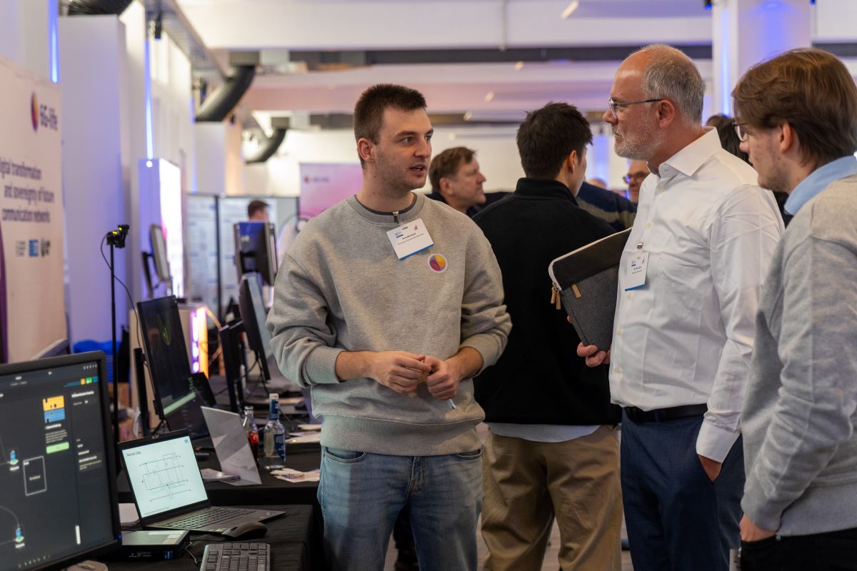 Benedikt Baier in front of the 6G-life booth, explaining the project on the Thinknet 6G Summit.