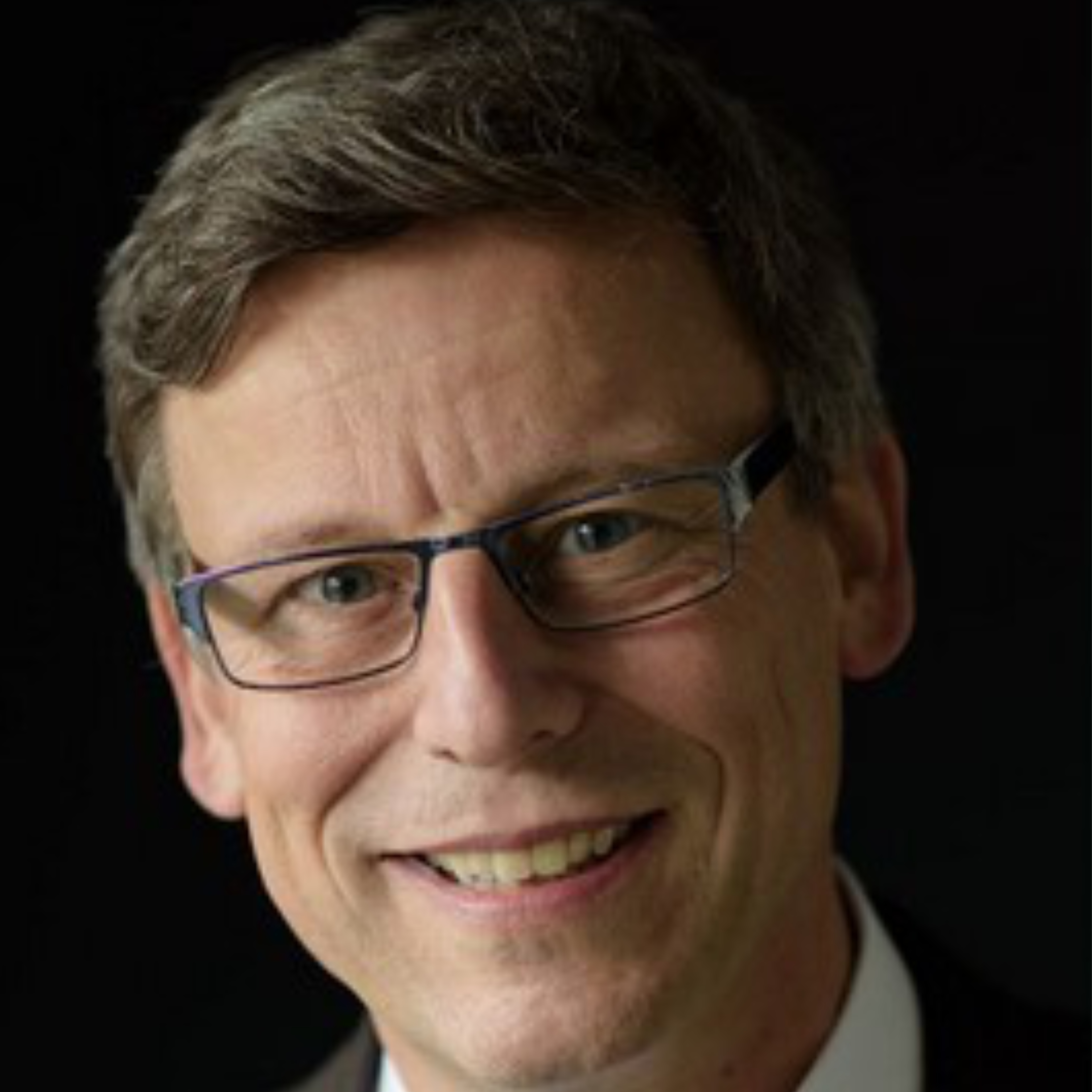 Bild von Andreas Nebeling der Elmos Semiconductor SE welches einen lächelnden Mann mit eckiger Brille und braunen Haaren zeigt, der vor einem schwarzen Hintergrund zu sehen ist