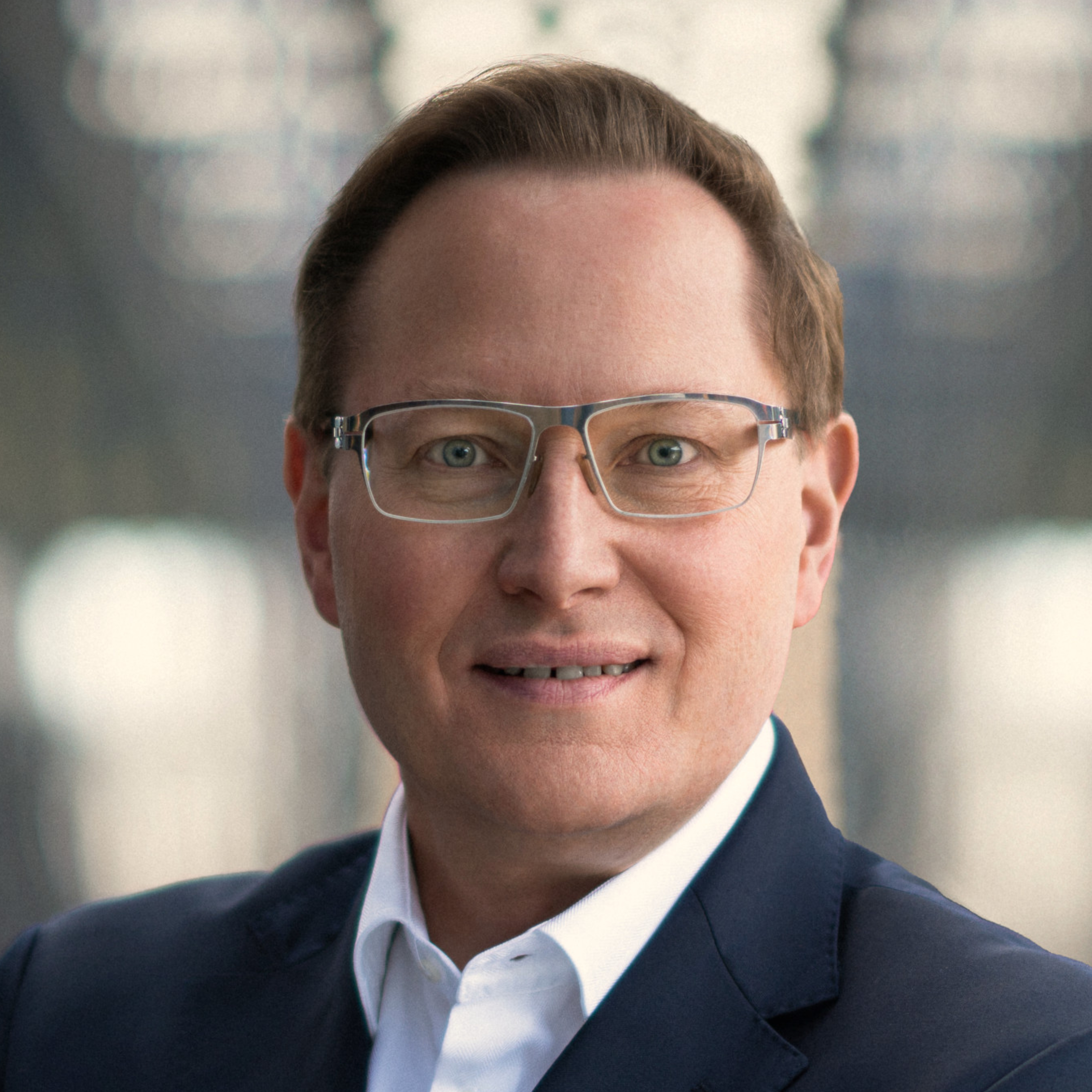 Portraitbild von Dr. Karlheinz Morgenroth, welches einen Mann mit dunkelblonden Haaren und Brille zeigt, der ein weißes Hemd mit schwarzem Sakko trägt