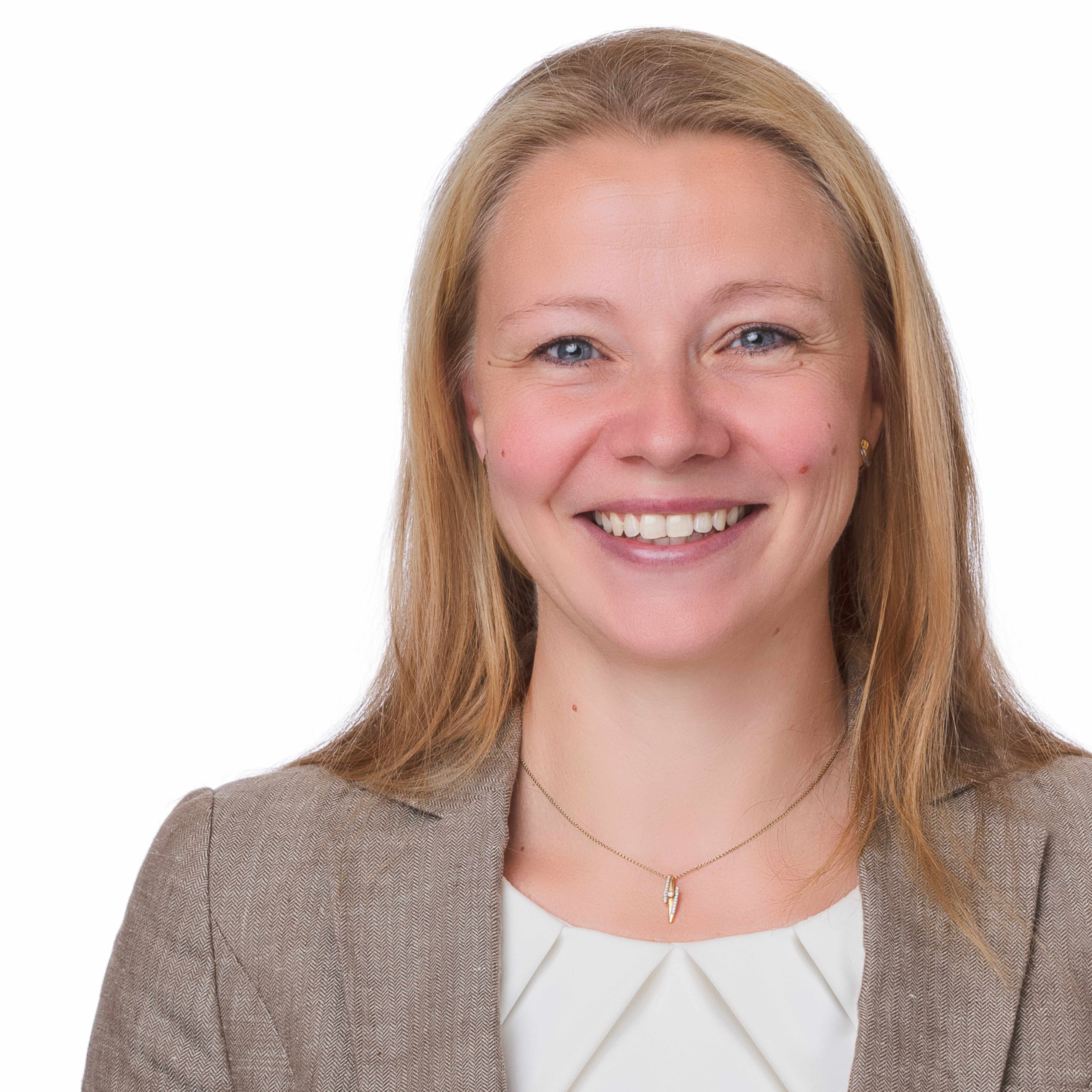 Portraitbild von Dr. Antje Nörtzold, einer Frau mit rot-blonden langen Haaren, die vor einem beigen hintergund fotografiert ist und eine beige Bluse und einen braunen Blazer darüber trägt.