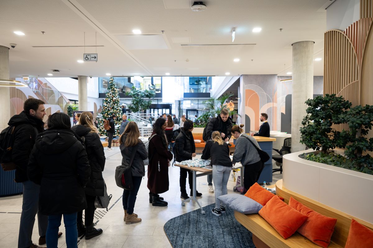 „Große Gruppe von Hackathon-Teilnehmenden steht auf einer Treppe für ein Gruppenfoto, im Hintergrund ist ein modernes Gebäude sichtbar.“