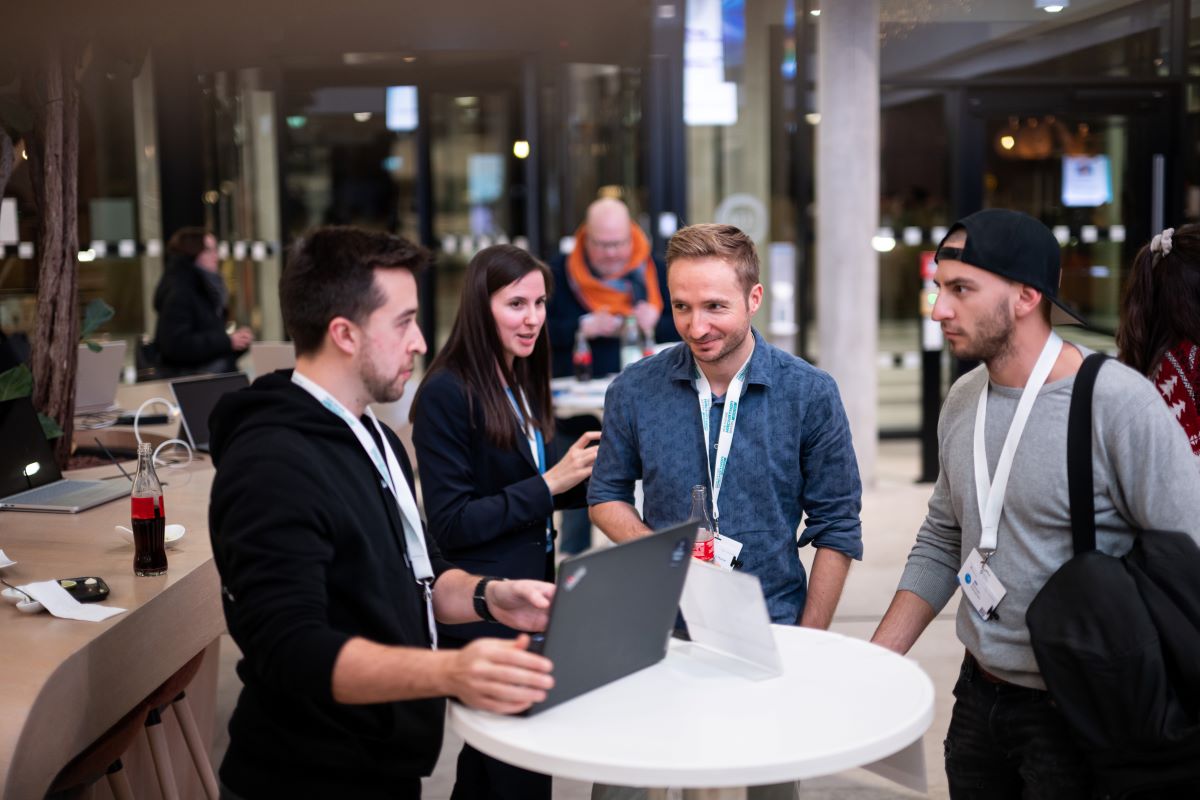 Eine Gruppe Menschen steht an einem Stehtisch und unterhält sich