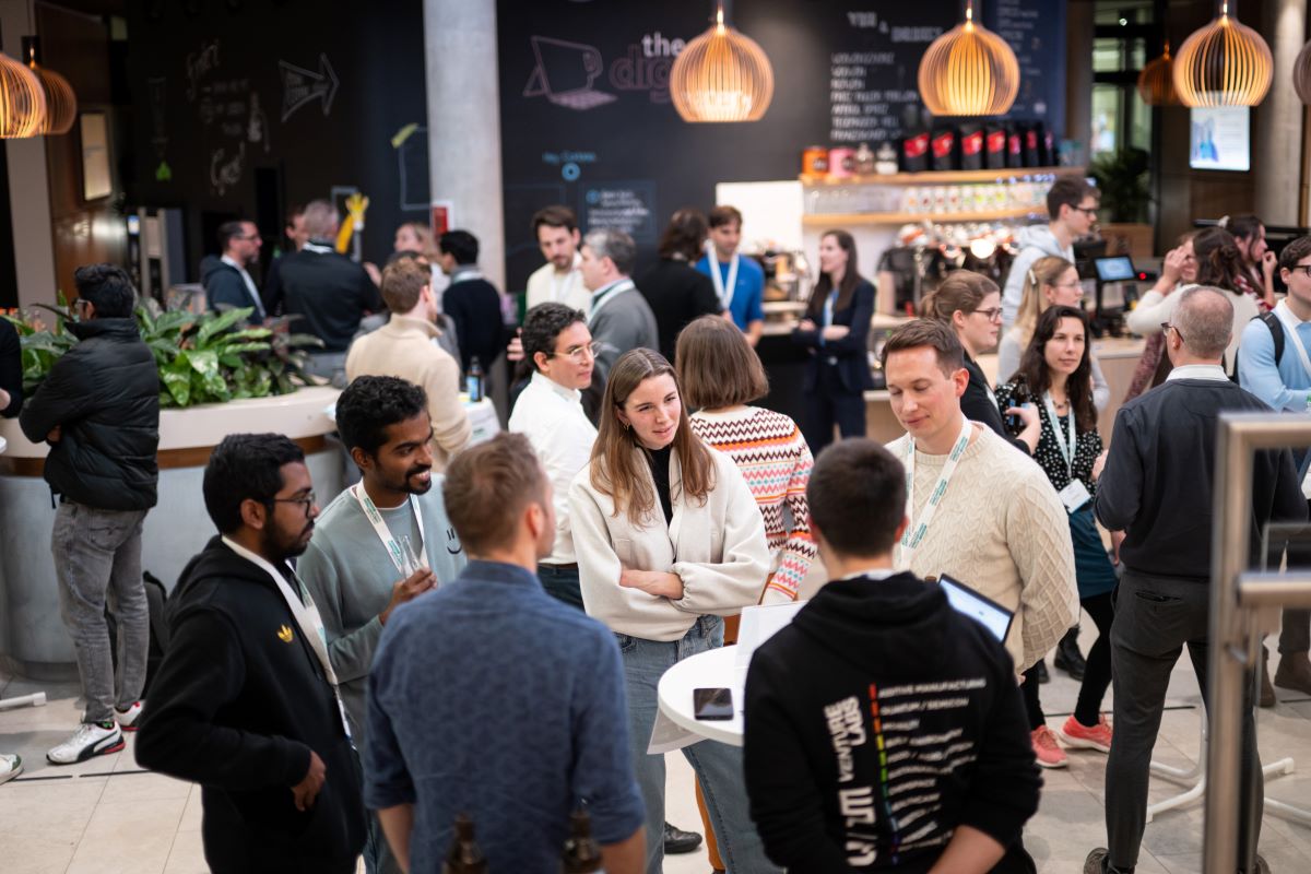 Menschen stehen um Stehtische und unterhalten sich 