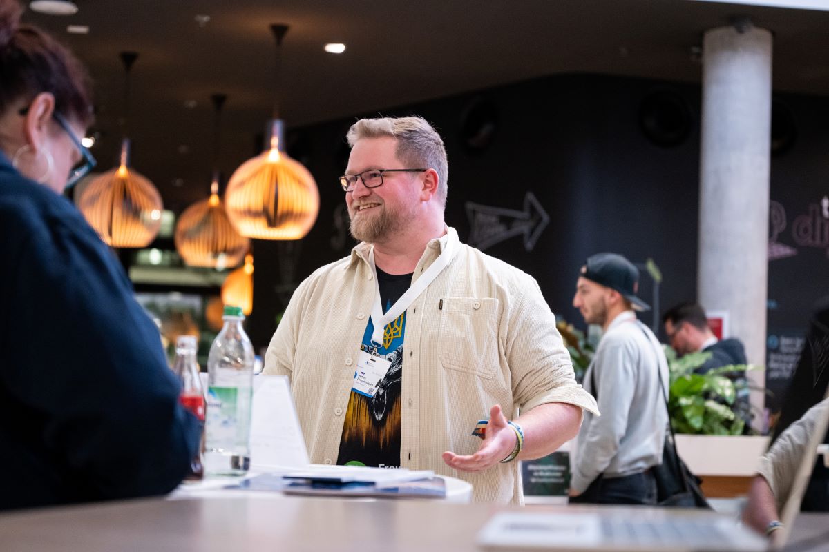 Ein Mann steht vor einem Stehtisch und lacht