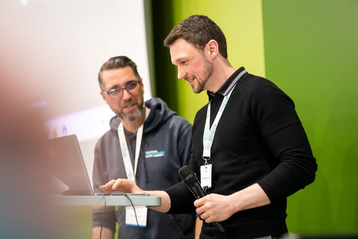 Zwei Männer stehen vor einem grünen Hintergrund