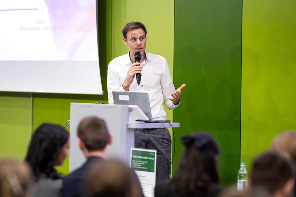 Ein Mann hält einen Vortrag vor einem grünen Hintergrund