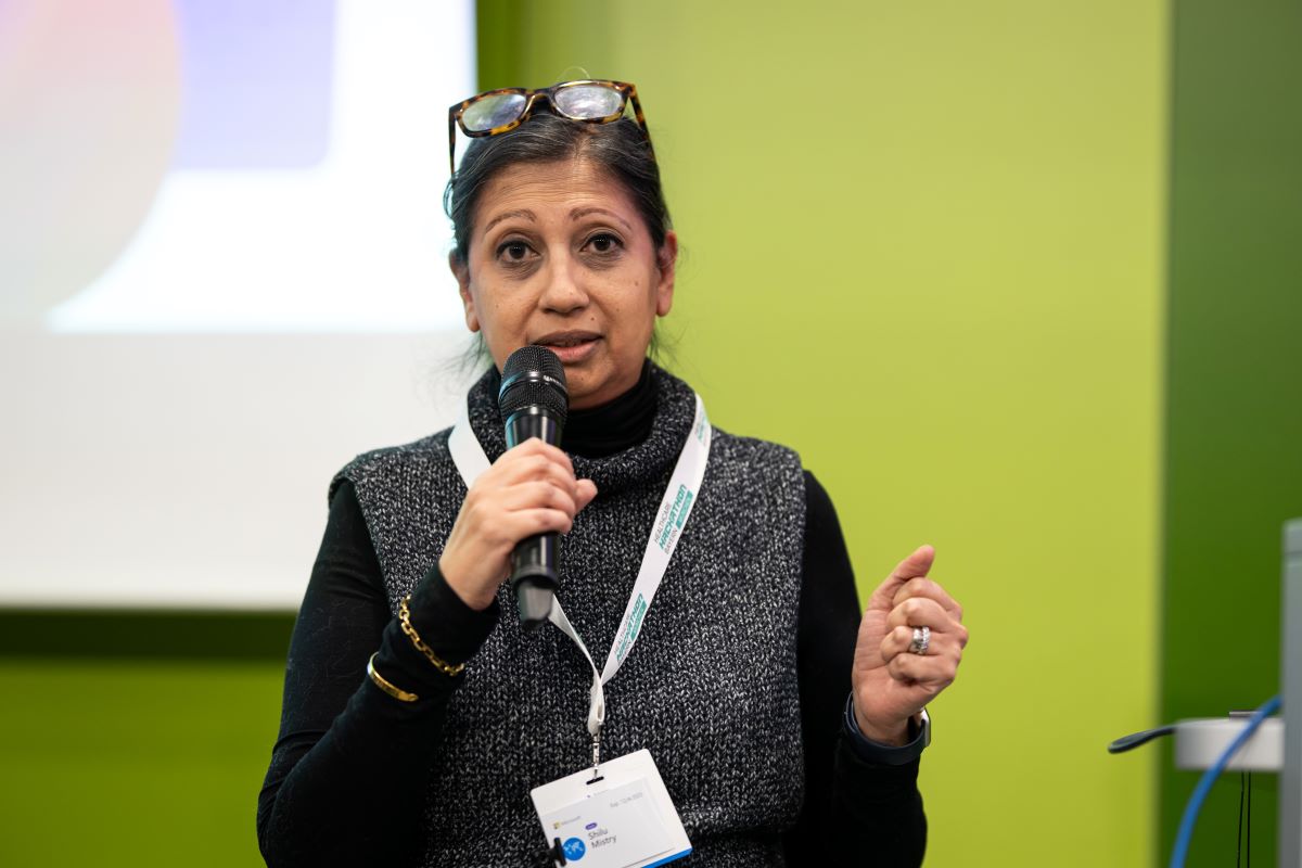 Eine Frau hält einen Vortrag, sie steht vor einem grünen Hintergrund