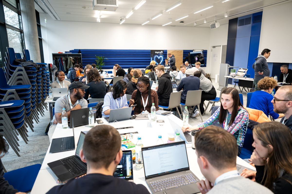 Menschen sitzen an Tischen und arbeiten an Laptops