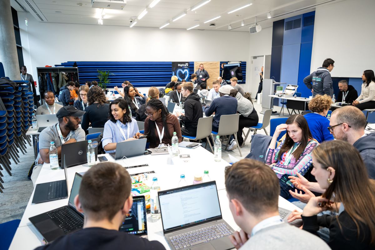 Menschen sitzen an Tischen und arbeiten an Laptops