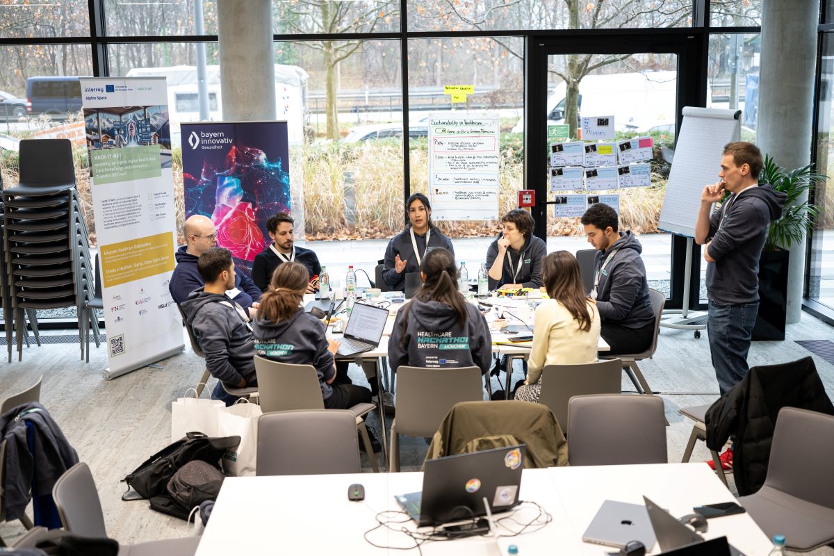 Mehrere Personen arbeiten an Laptops, während sie an einem Tisch zusammensitzen und Ideen austauschen.
