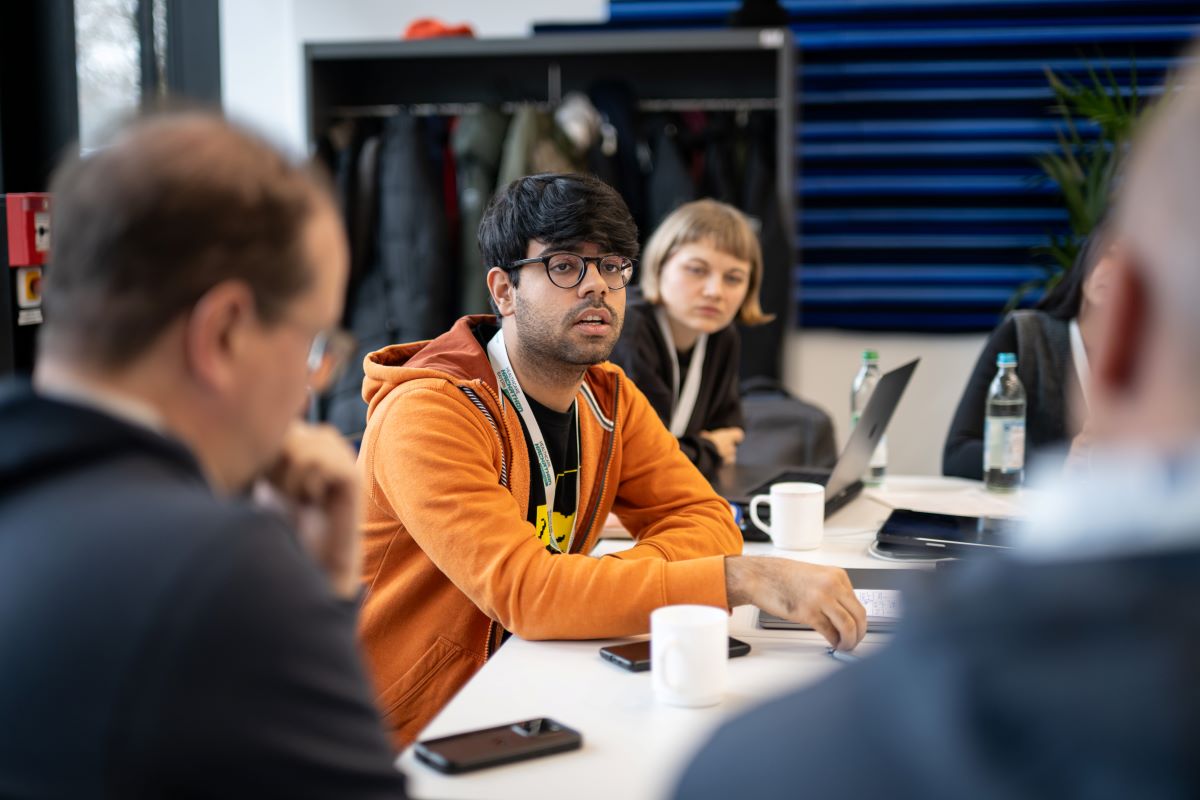vier Menschen sitzen an einem Tisch und diskutieren