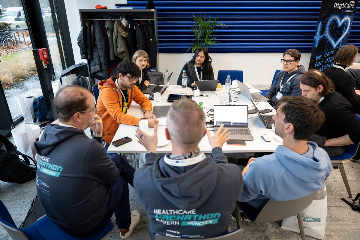 Mehrere Personen arbeiten an Laptops, während sie an einem Tisch zusammensitzen und Ideen austauschen.