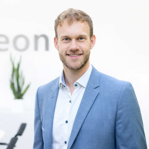 auf dem Bild ist ein Herr mit weißem Hemd und blauem Sakko zu sehen