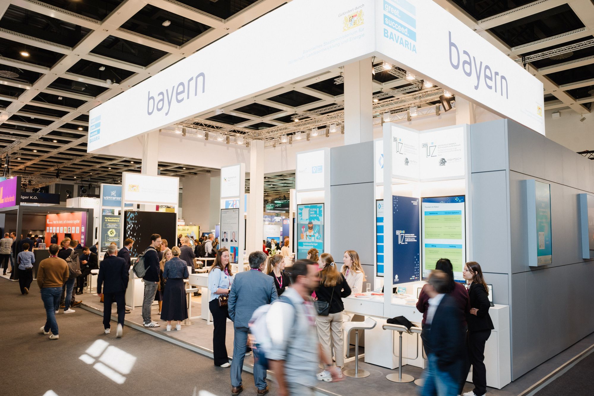 Messestand mit der Aufschrift »bayern« und »bavaria« auf einem Fachmessegelände mit mehreren Besuchern