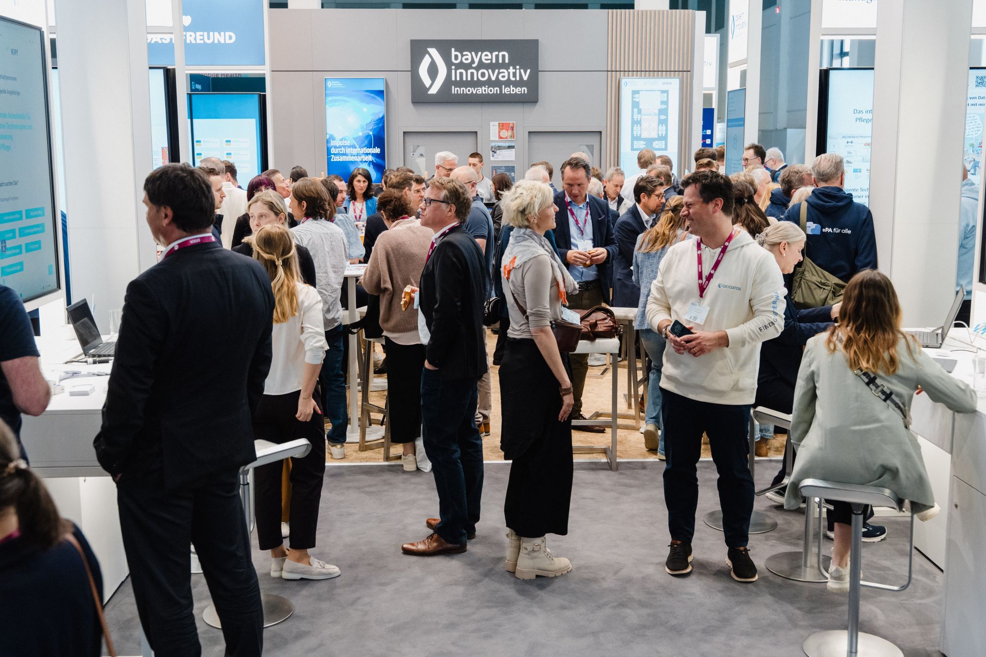 Menschenmenge auf einer Messe vor einem Stand mit dem Schriftzug 'bayern innovativ Innovation leben'