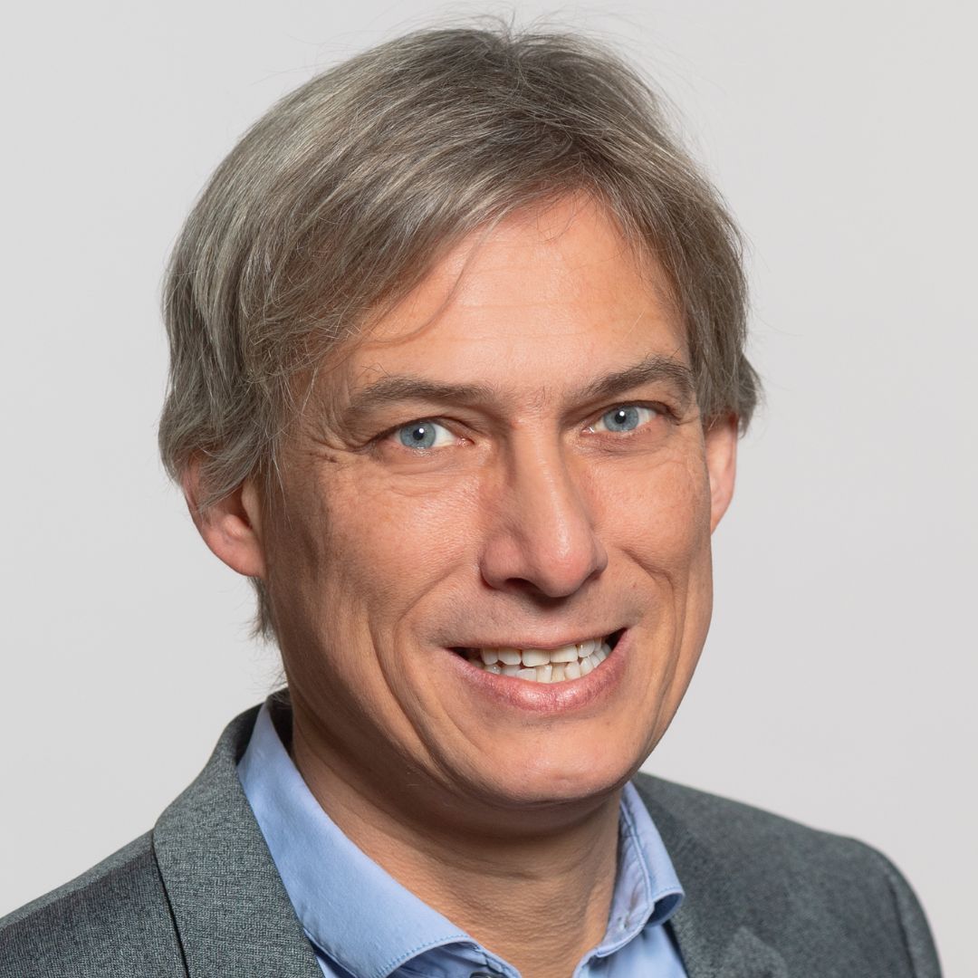 Mann mit grau-braunen Haaren und grauer Jacke