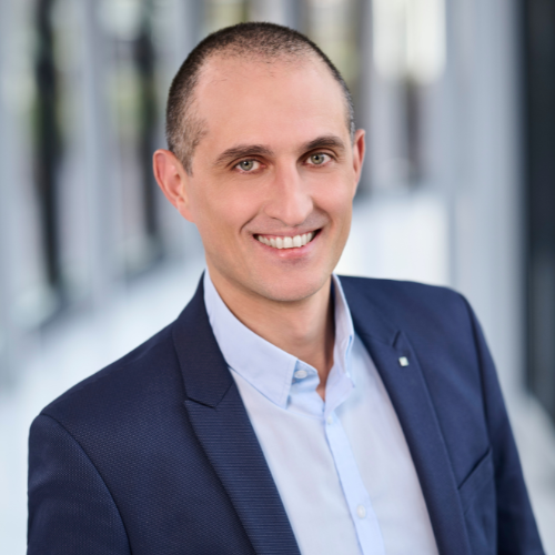 Mann mit kurzen braunen Haaren, dunkelblauen Sakko und hellblauen Hemd