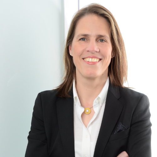 Frau mit langen dunkelblonden Haaren, weißer Bluse und schwarzem Blazer