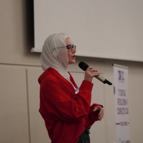 Frau mit weißem Kopftuch und rotem Oberteil und Brille