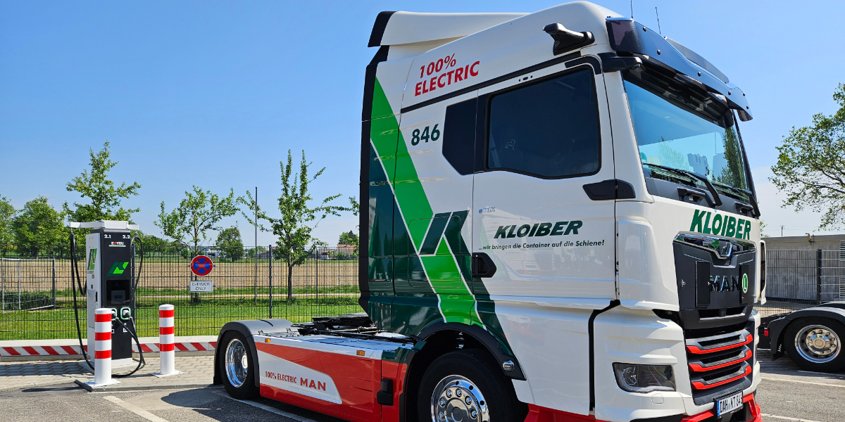 Zu sehen ist ein elektrischer LKW vor einer Ladesäule.