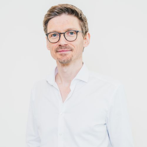 Auf dem Bild ist ein Herr mit Brille und weißem Hemd zu sehen
