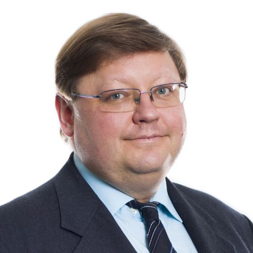 Porträt eines Mannes mit Brille, Anzug, hellblauem Hemd und gestreifter Krawatte vor weißem Hintergrund