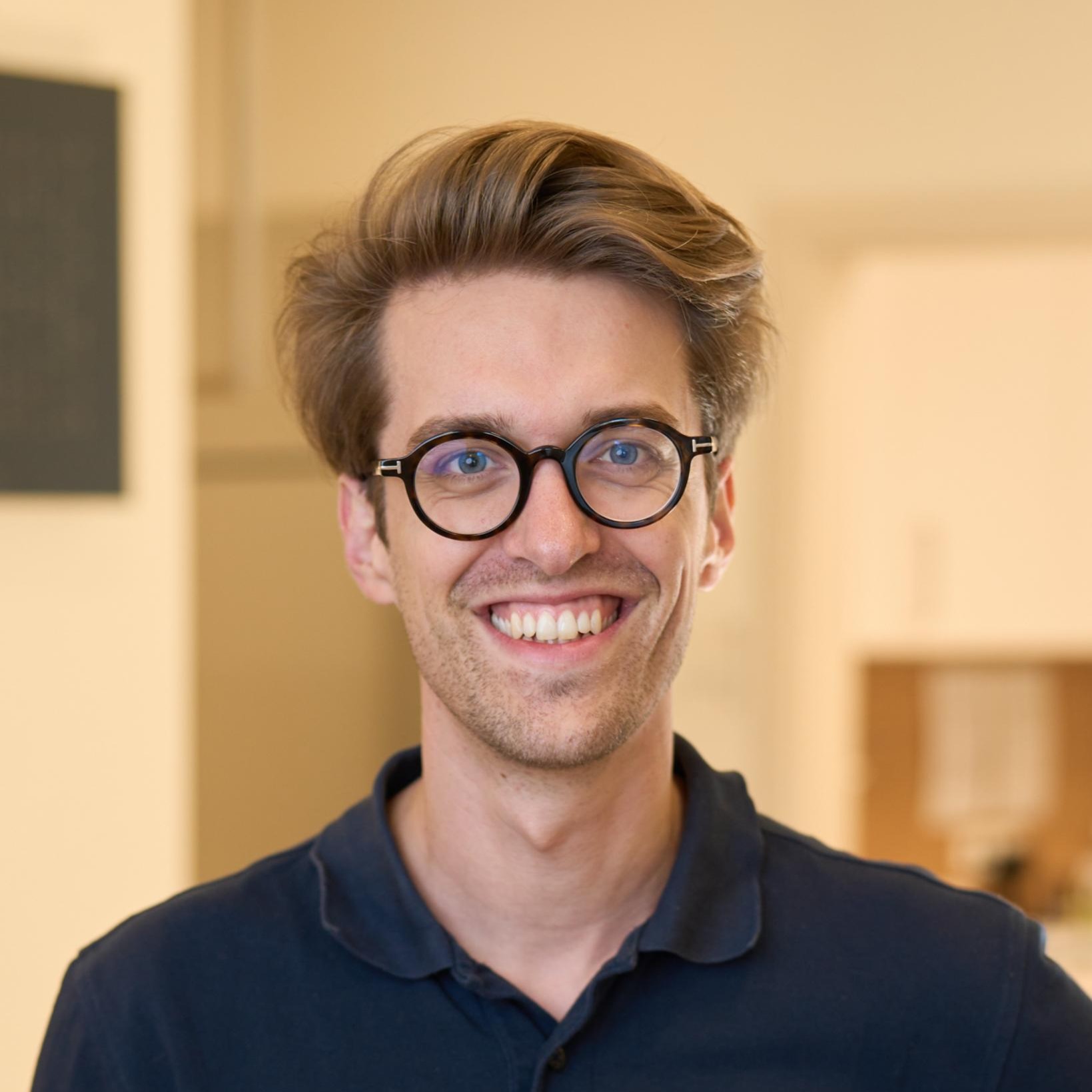 Auf dem Bild ist ein Herr mit Brille und schwarzem Hemd zu sehen