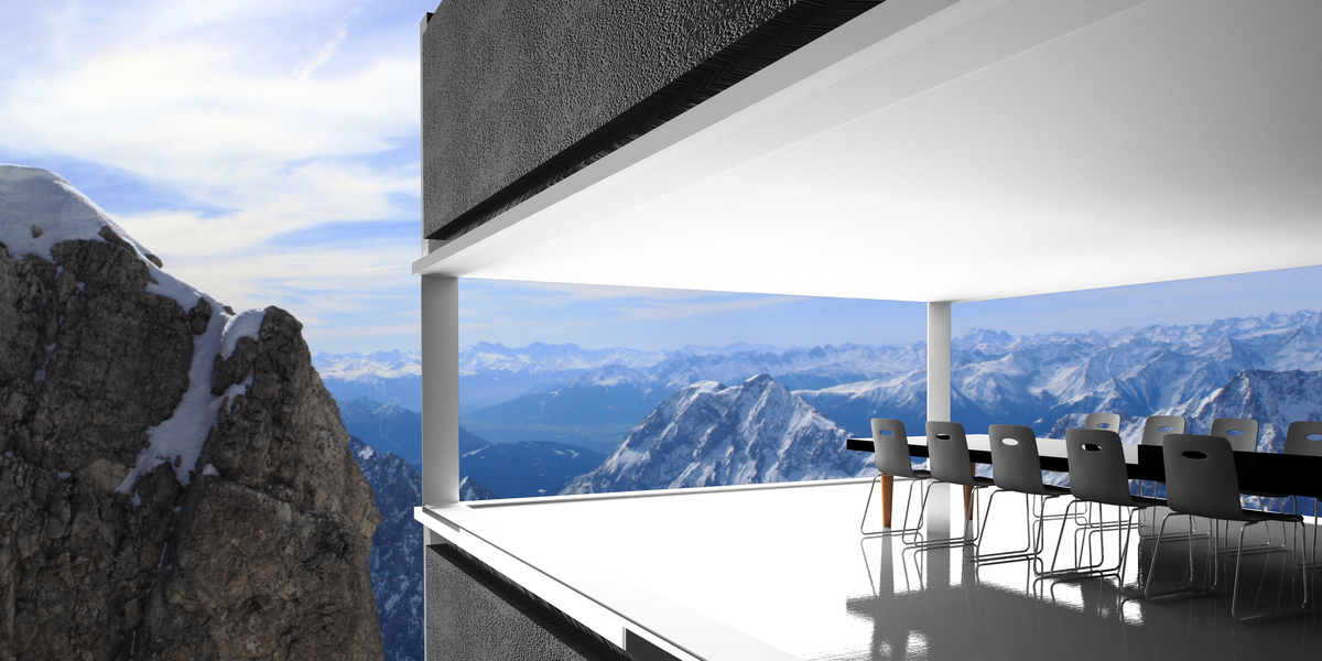 Mit Ausblick auf ein Gebirge befindet sich ein großer, langer Tisch mit Meetingstühlen in einer modernen, offenen Architektur