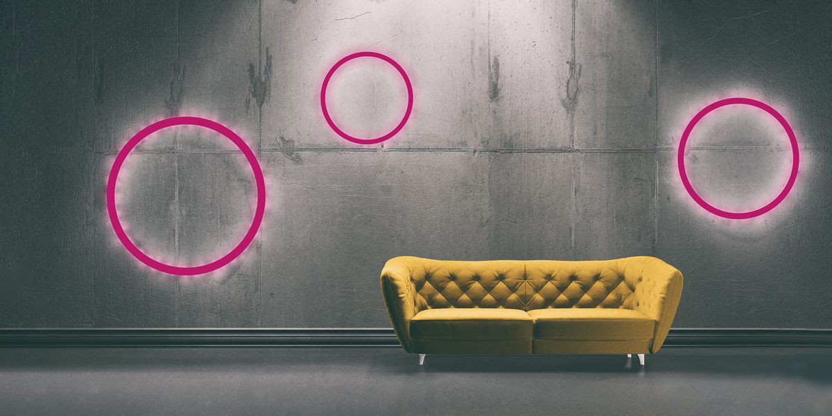 Gelbe Couch vor einer Wand mit pinken Kreisen.