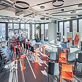 Heller, modern eingerichteter Konferenzraum bei Design Offices München Bogenhausen mit bodentiefen Fenstern, stilvollen Deckenleuchten und farbenfrohen Sitzgelegenheiten für Workshops und Events.