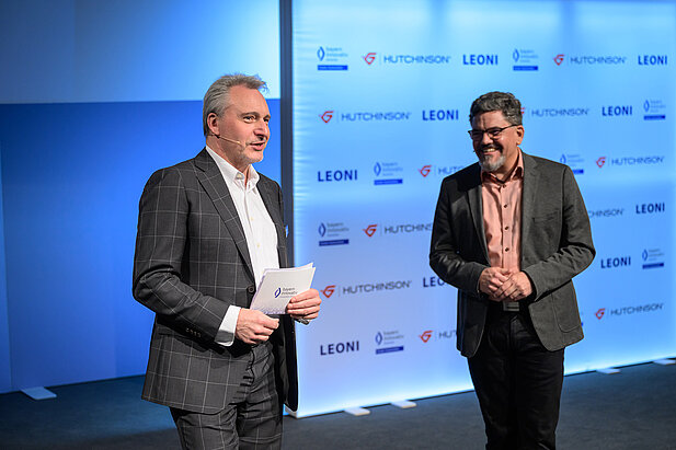 Dr. Andreas Böhm von Bayern Innovativ und ein Referent auf der Bühne beim Kooperationsforum Bordnetze 2025