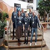 Mehrere Personen stehen auf einer Treppe in einem Empfangsbereich.