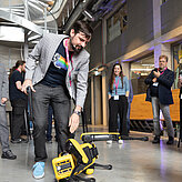 Das Bild zeigt einen Mann der über einen Roboter Hund gebeugt ist. 