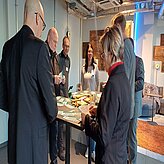 Auf diesem Bild ist eine Gruppe von Menschen zu sehen, die um einen Tisch stehen, auf dem verschiedene Gegenstände liegen.