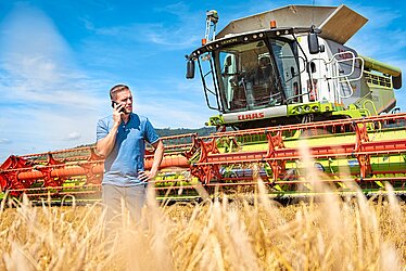 Bild von Andreas Dörr, der telefonierend auf einem Feld vor einem Mähdrescher steht