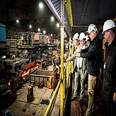 Teilnehmende der Delegation tragen Schutzkleidung und Helme während einer Besichtigung einer Produktionsstätte mit laufenden Maschinen. Aufgenommen bei der Delegationsreise in Kanada.