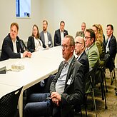 Personen sitzen in einem Konferenzraum an einem Tisch, hören einer Präsentation oder Diskussion zu. Die Szene stammt von einem Termin der Delegationsreise in Kanada.