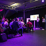 Das Bild zeigt einen Mann der vor einem Publikum spricht