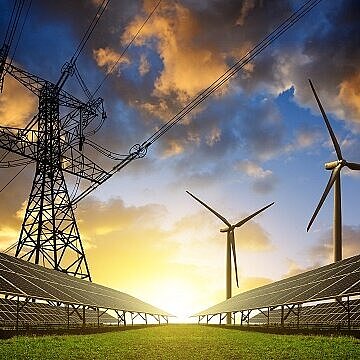 Das Bild zeigt Strommasten, Windräder und Solarpaneele vor einem Sonnenuntergang.