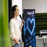 Eine Frau hält einen Vortrag, sie trägt eine weiße Bliuse