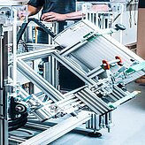 Teil eines komplexen Aluminiumprofilsystems mit montierten mechanischen und elektronischen Komponenten und einer Person im Hintergrund