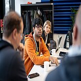 vier Menschen sitzen an einem Tisch und diskutieren