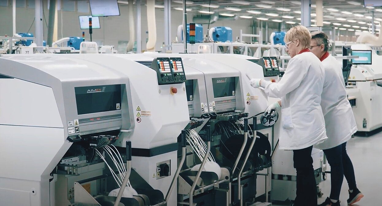 Zwei Mitarbeitende in Schutzkleidung bedienen Maschinen