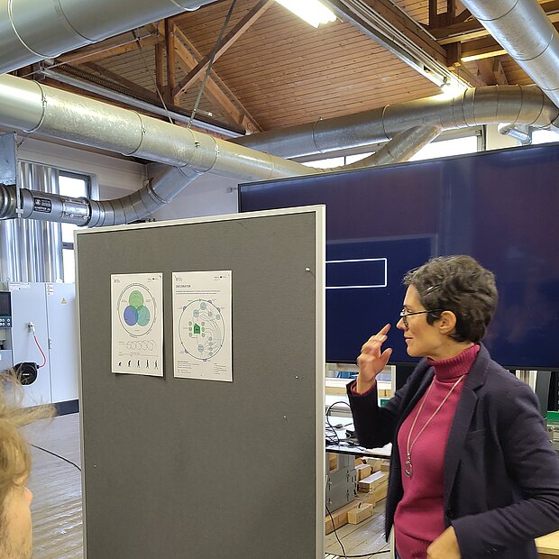 Referentin vor einer Pinnwand mit zwei Postern. 