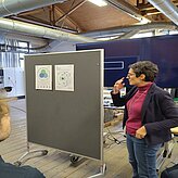 Referentin vor einer Pinnwand mit zwei Postern. 