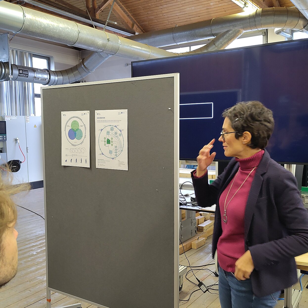 Referentin vor einer Pinnwand mit zwei Postern. 