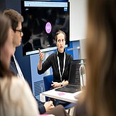  Eine Frau hält eine Präsentation vor einer Gruppe von Menschen.